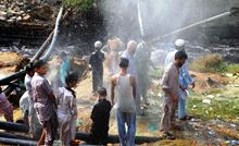 People cooling besid a broken water pipe in Pakistan